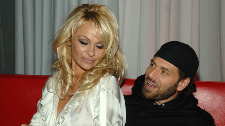 Pamela Anderson looking down and sitting next to Rick Salomon