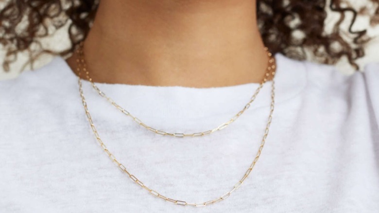 A woman wearing layered paper clip chain necklaces