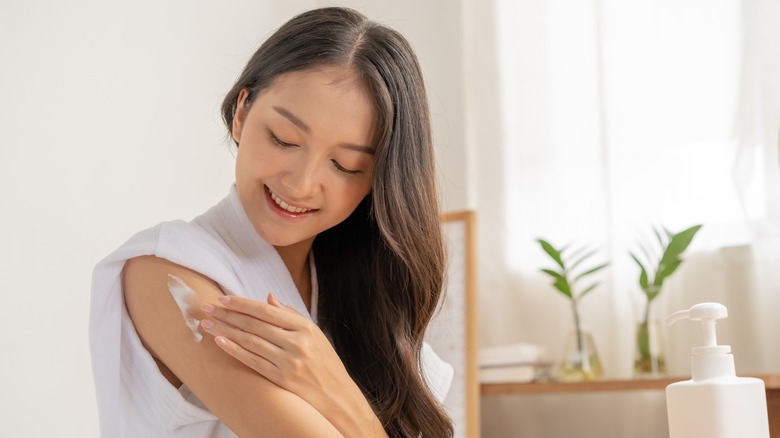 Happy woman using moisturizer 