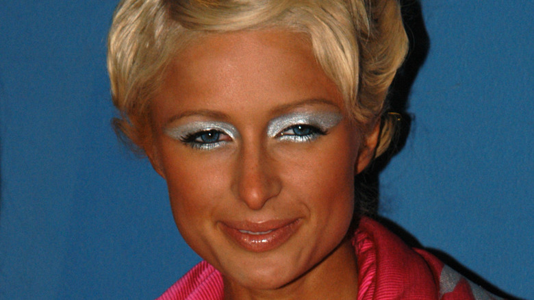 Paris Hilton smiling with a heavy fake tun and silver eyeshadow