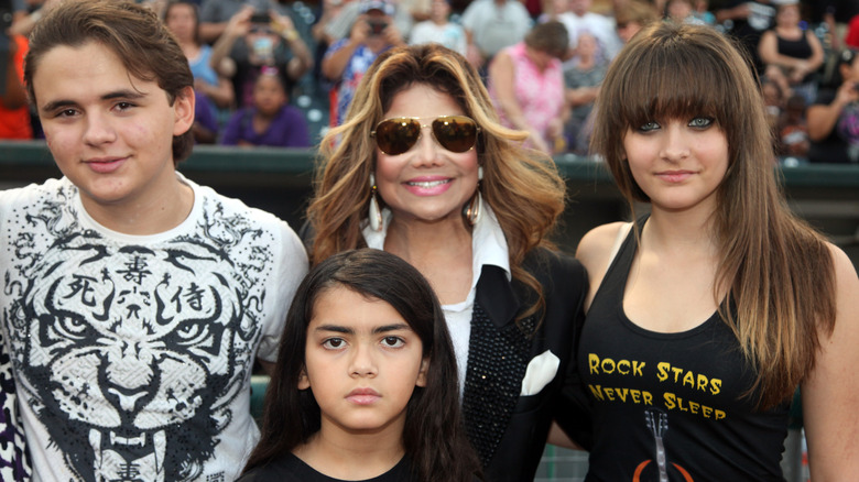 Prince, Katherine, Blanket, and Paris Jackson smiling at a baseball game in 2012