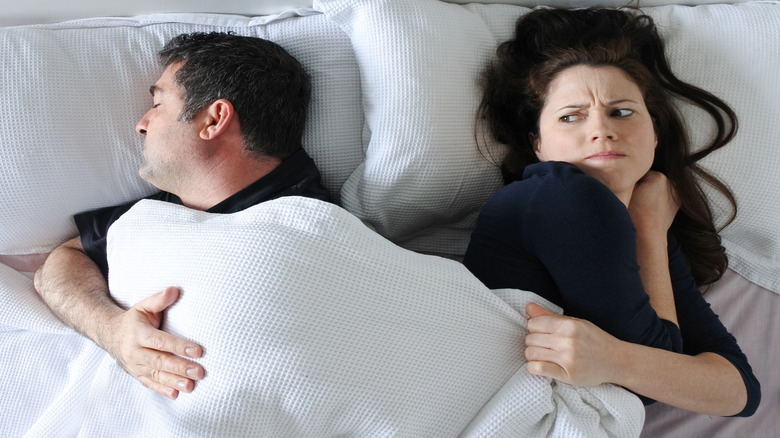 Couple fighting over hogging blanket