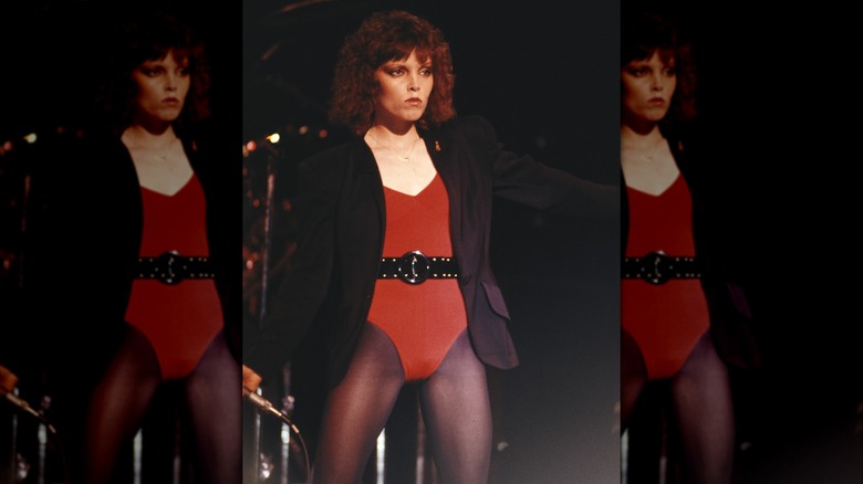Pat Benatar posing and holding a microphone on stage