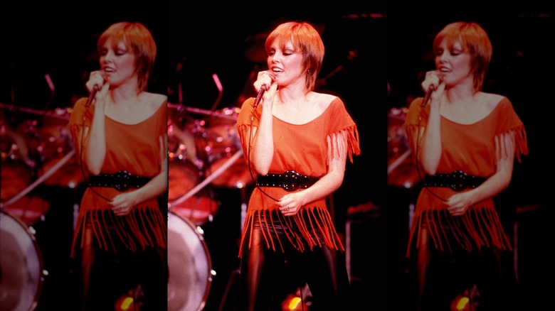 Pat Benatar singing into microphone in fringe top