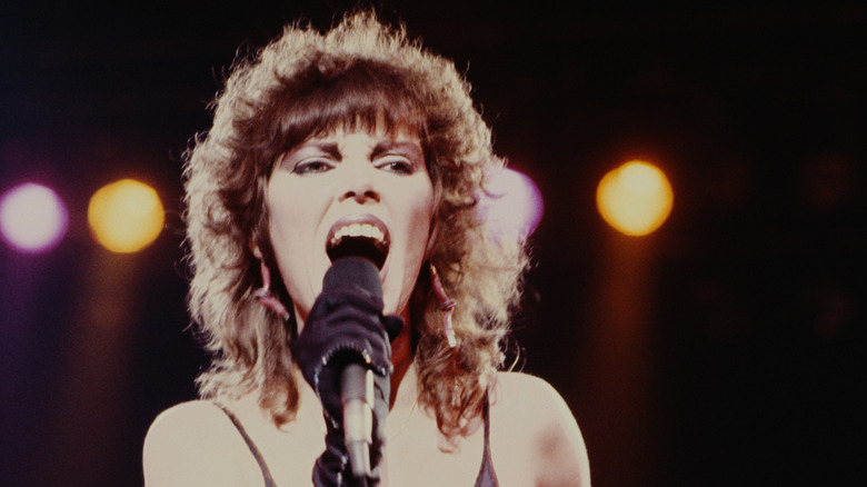 Pat Benatar singing into a microphone on stage