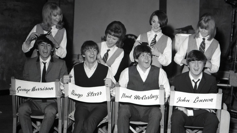 A black-and-white photo of The Beatles, Pattie Boyd, and others on the set of 'A Hard Day's Night'