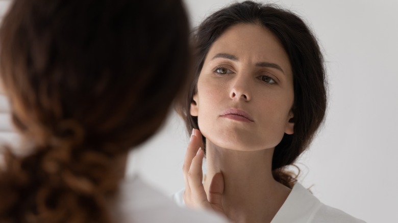 woman examining face in mirror