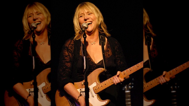 Pegi Young smiling and playing her guitar