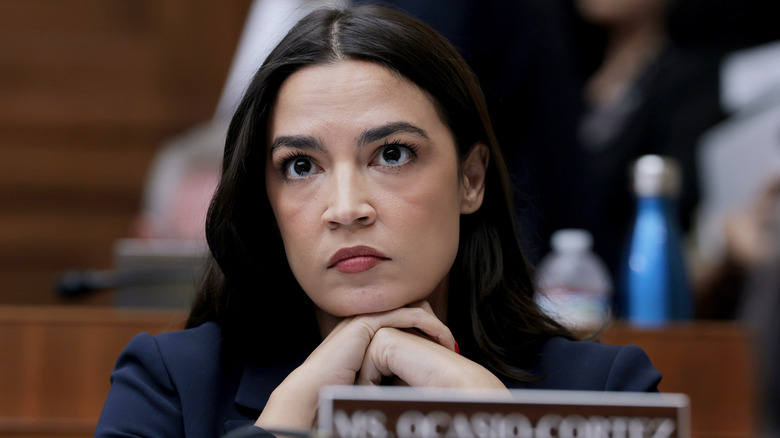 Alexandria Ocasio-Cortez looking concerned with her chin resting on her hands