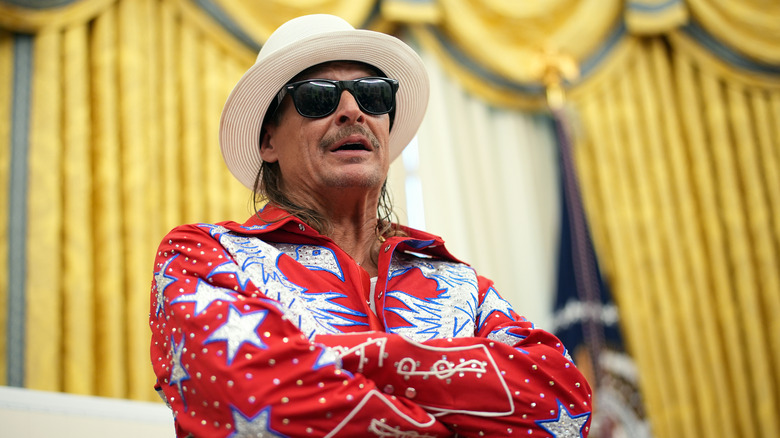 Kid Rock wearing a red white and blue jumpsuit in the Oval Office.