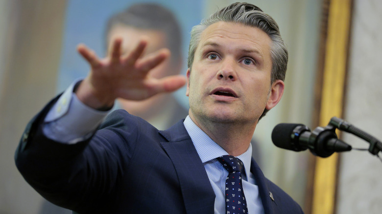 Pete Hegseth gesturing with hand at podium