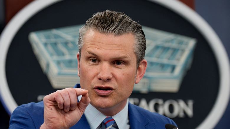 Pete Hegseth speaking in a blue suit during a press conference at the Pentagon.
