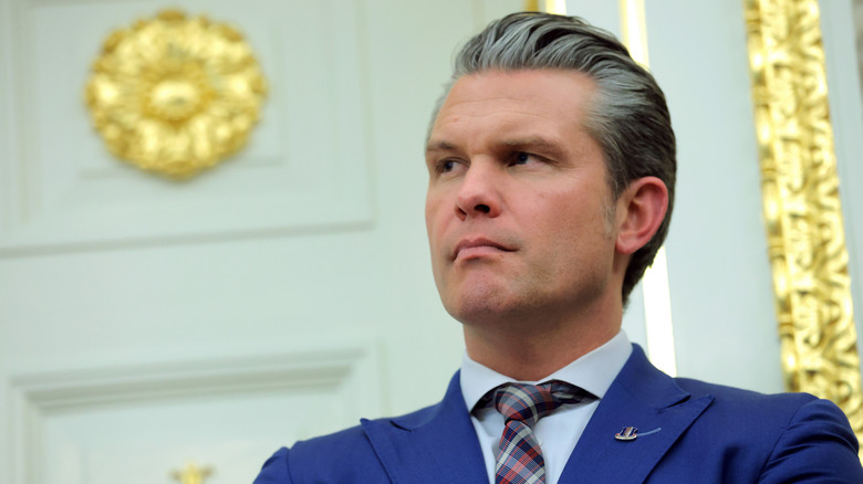 Pete Hegseth listening intently to something off camera in the White House Oval Office
