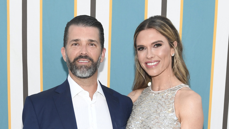 Donald Trump Jr. in a suit posing at an event with Bettina Anderson in a silver dress