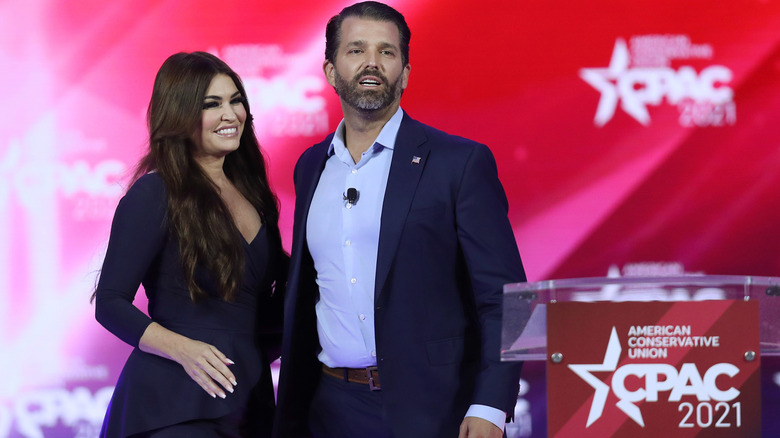 Kimberly Guilfoyle and Donald Trump Jr. smiling on stage at CPAC 2021
