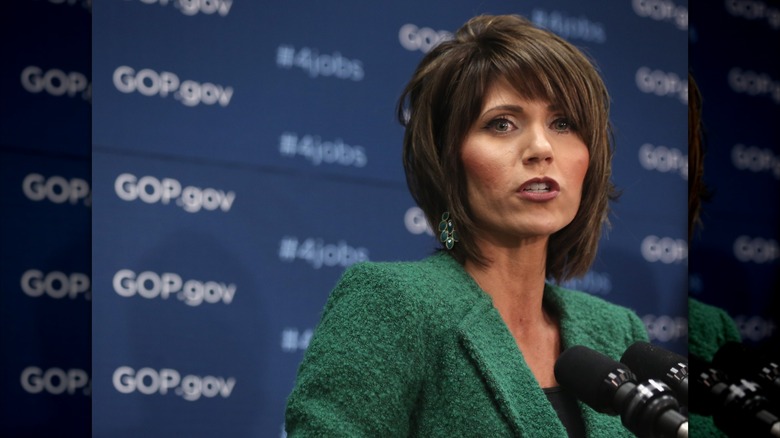 Kristi Noem with a short haircut behind two microhpones.