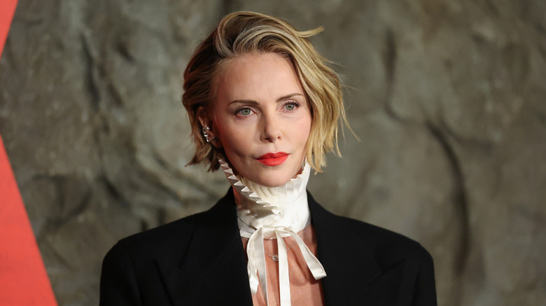 Charlize Theron posing on the red carpet in a white frilly collar.