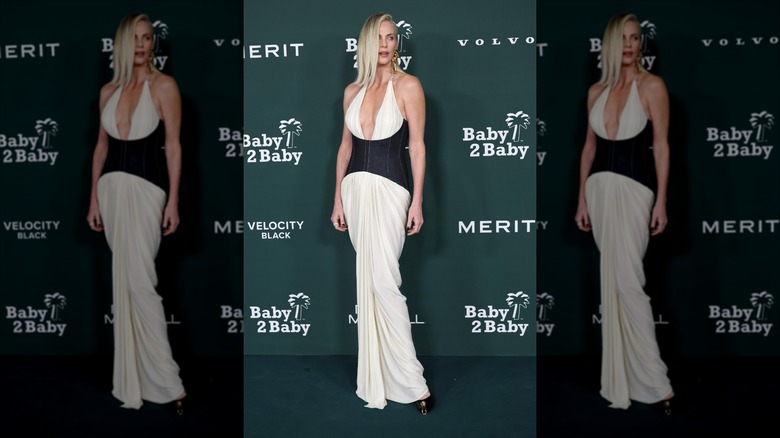 Charlize Theron on the Baby 2 Baby gala red carpet in a draped white dress under a denim corset