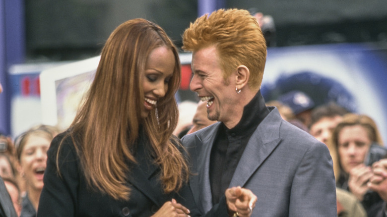 Iman, wearing a black trouser suit, and her husband, British singer, songwriter and actor David Bowie, who wears a grey coat over a black banded-collar shirt, attend Bowie's Hollywood Walk of Fame star ceremony on Hollywood Boulevard in the Hollywood neighbourhood of Los Angeles, California, 12th February 1997