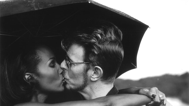 Iman and David Bowie share a kiss under an umbrella