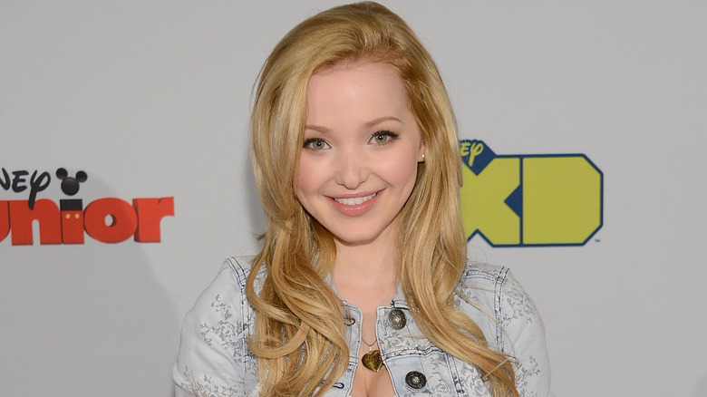 Dove Cameron smiling on a red carpet in 2013