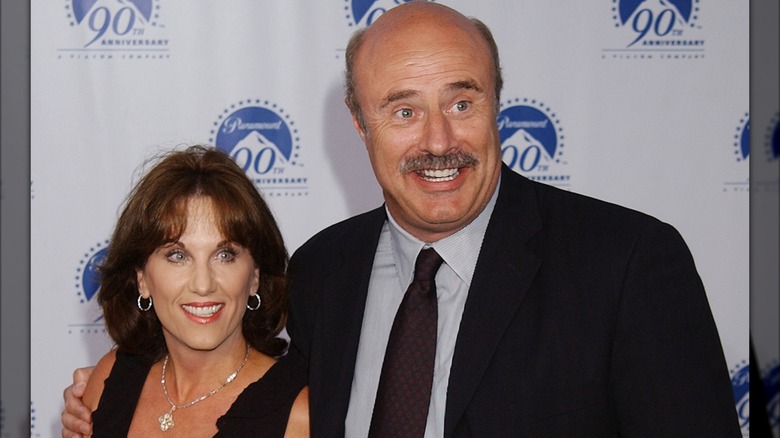Phil McGraw with arm around Robin McGraw both smiling
