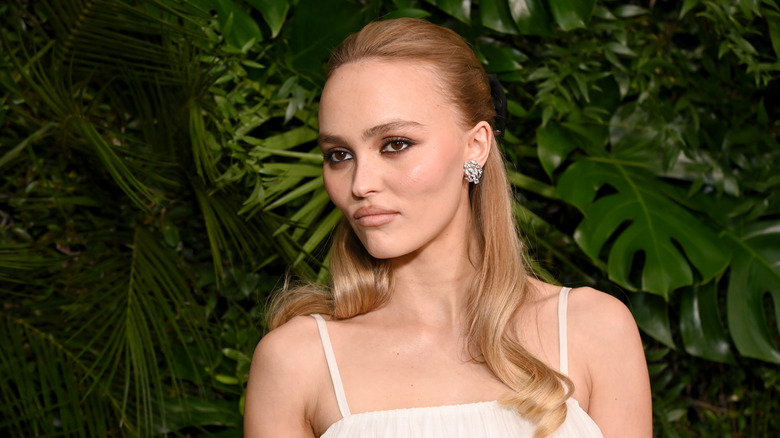 Lily-Rose Depp in white dress against a leafy background
