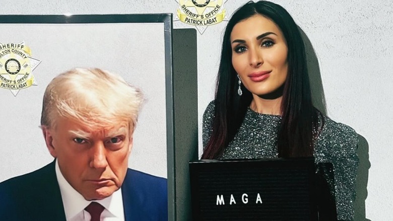 Laura Loomer poses in front of a photo of Donald Trump (2025)