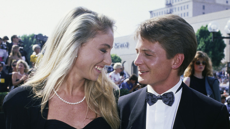Tracy Pollan and Michael J. Fox smiling lovingly at each other in matching all-black ensembles