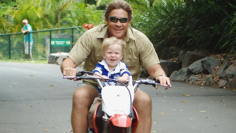Robert Irwin riding a motorcycle with Steve Irwin