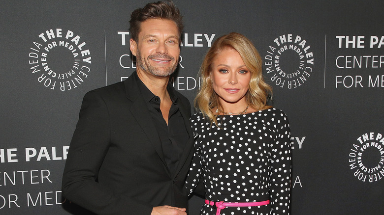 Ryan Seacrest wearing black and Kelly Ripa wearing a black and white polka dot dress