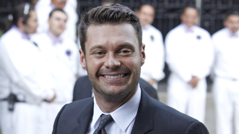 Ryan Seacrest wearing a black suit and tie