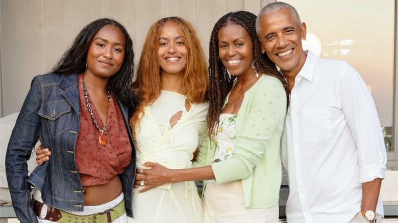 The Obama family standing together with their arms around each other.