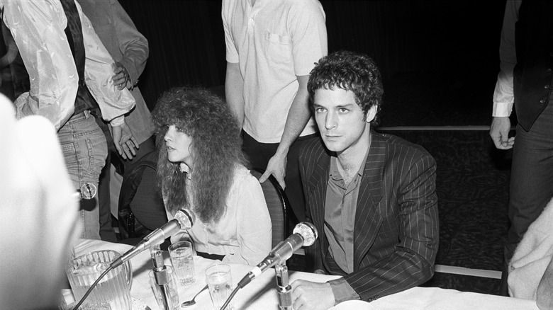 Black and white photo Stevie Nicks (left) and Lindsey Buckingham (right) at a Fleetwood Mac press conference at the Hotel St Moritz in New York City on November 9, 1979, sat next to each other at a long table surrounded by press
