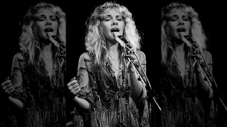 Black and white photograph of Stevie Nicks performing on stage in 1978 wearing a floaty peasant dress and her hair long and curly
