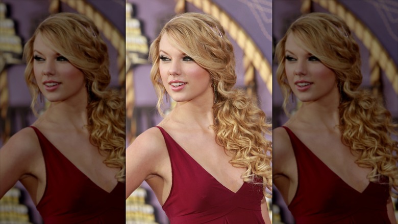 Taylor Swift in a red dress, looking over her shoulder, in front of a purple background.