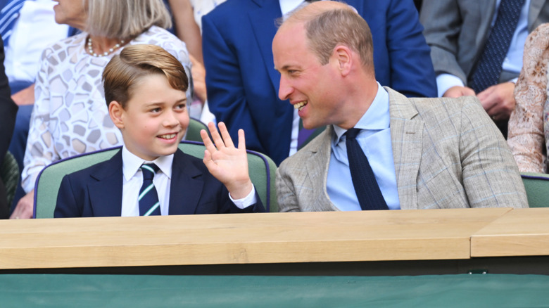 Prince William and Prince George smiling while speaking to each other at an event