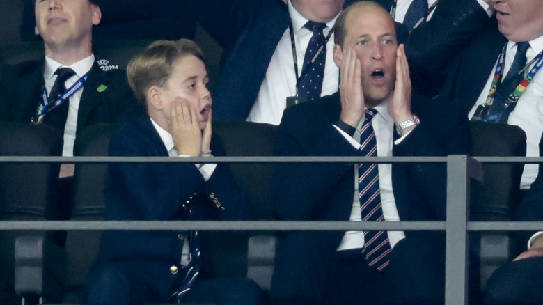 Prince George and Prince William wearing similar expressions of shock while watching a match