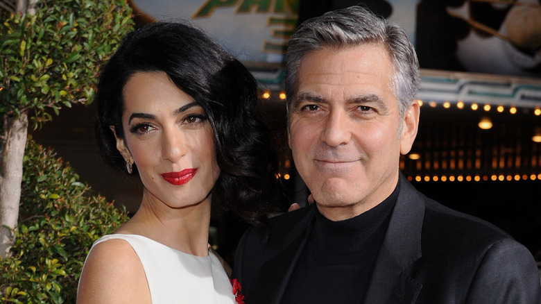 Amal Clooney and George Clooney posing at event