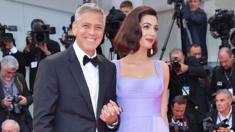 Amal Clooney and George Clooney posing at event