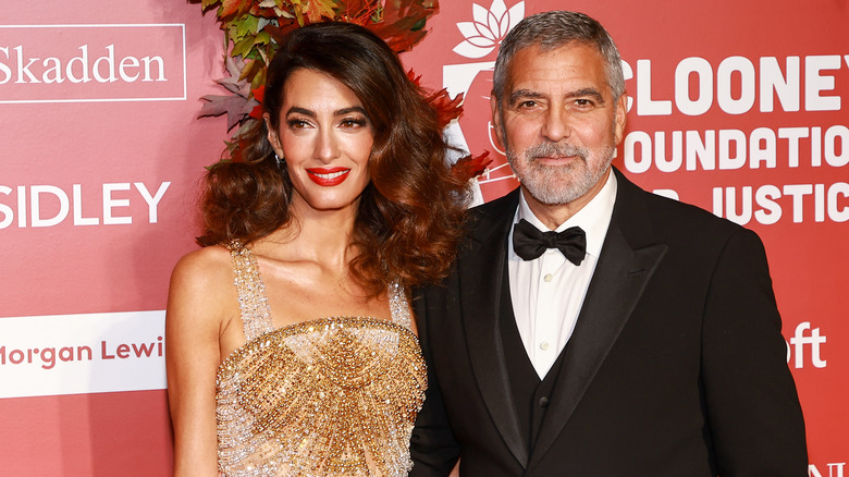 Amal Clooney and George Clooney posing at event
