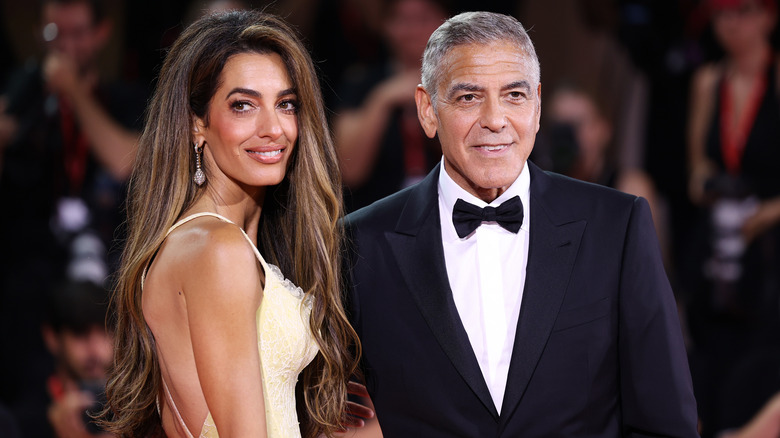 Amal Clooney and George Clooney posing at event