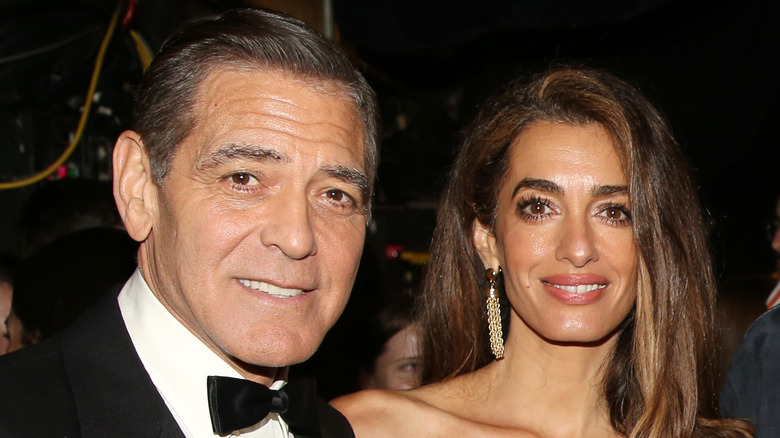 Amal Clooney and George Clooney posing at event