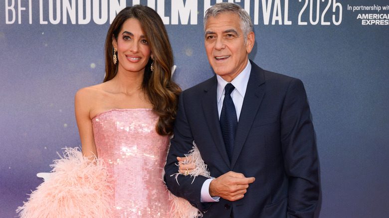 Amal Clooney and George Clooney posing at event