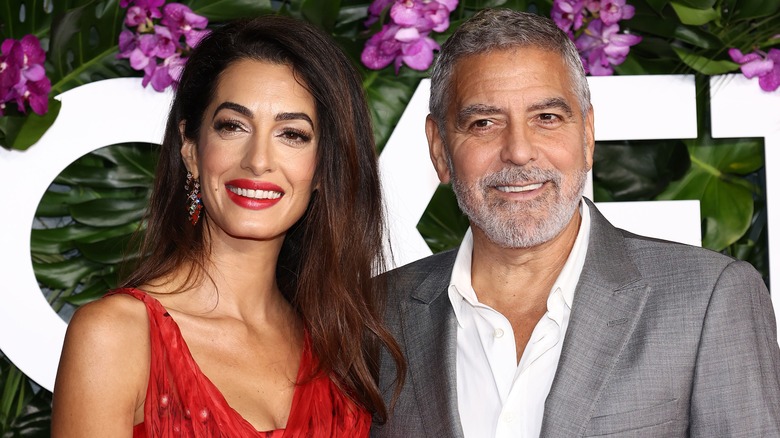 Amal Clooney and George Clooney posing at event