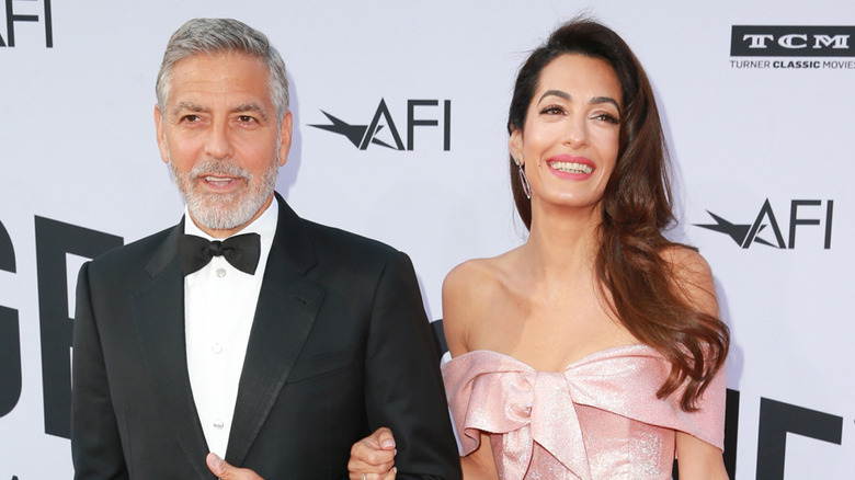 Amal Clooney and George Clooney posing at event