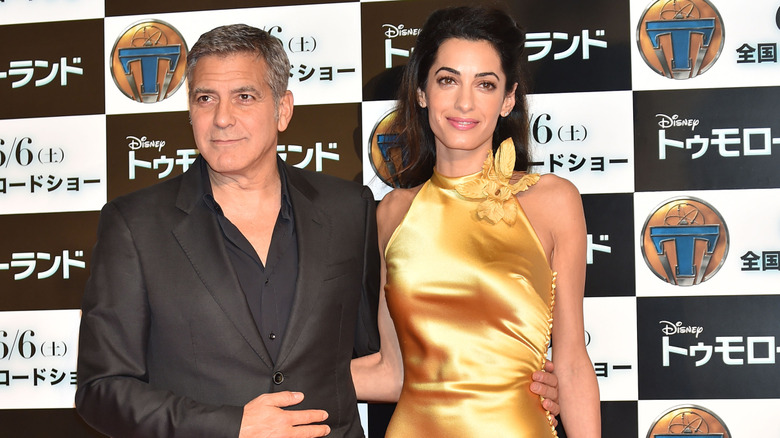 Amal Clooney and George Clooney posing at event