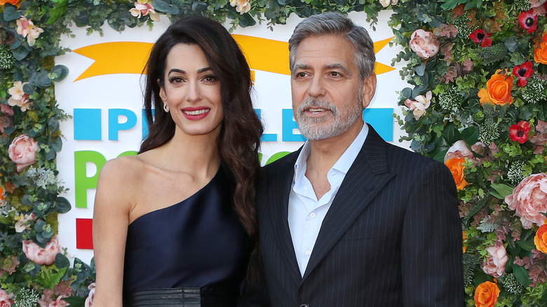 Amal Clooney and George Clooney posing at event