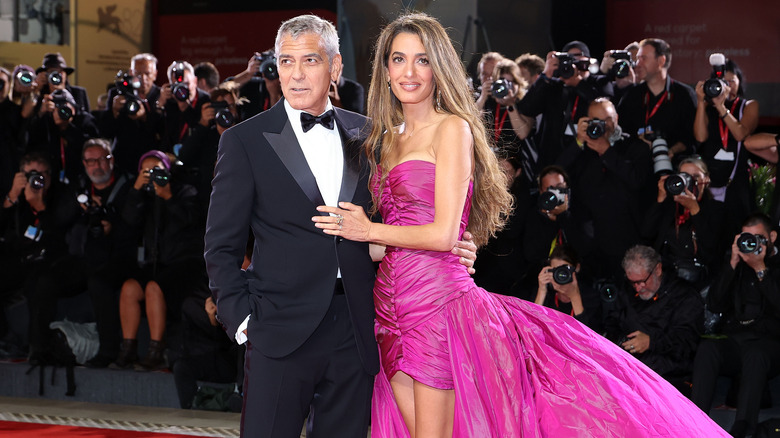 Amal Clooney and George Clooney posing at event