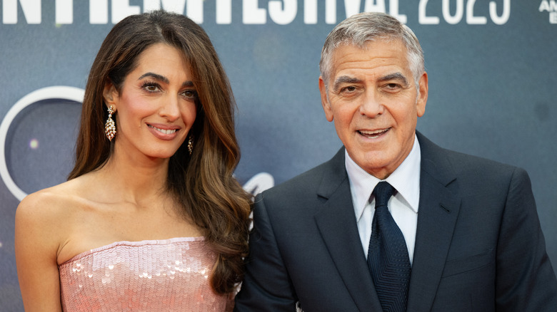Amal Clooney and George Clooney posing at event